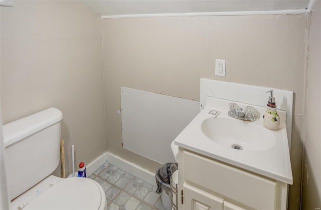 half bath with toilet, vanity, and baseboards