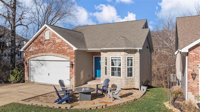 view of front of home featuring an outdoor fire pit, a garage, a shingled roof, concrete driveway, and stone siding