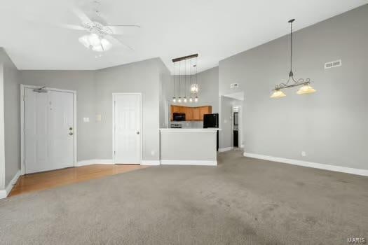 unfurnished living room featuring ceiling fan, a towering ceiling, visible vents, and baseboards