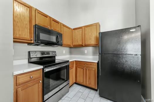 kitchen with brown cabinets, black appliances, and light countertops