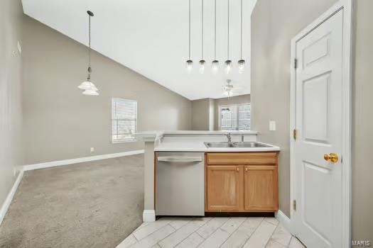 kitchen featuring pendant lighting, light countertops, stainless steel dishwasher, open floor plan, and a sink