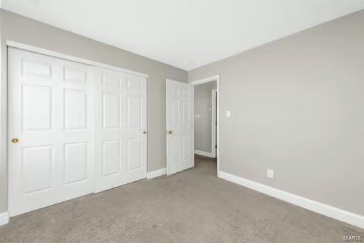 unfurnished bedroom featuring carpet floors, baseboards, and a closet