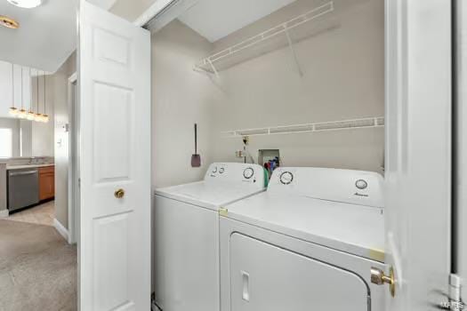 clothes washing area featuring laundry area, washer and clothes dryer, and light colored carpet