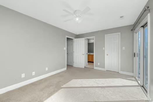 bedroom featuring a ceiling fan, light colored carpet, ensuite bath, and baseboards