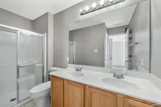 bathroom featuring double vanity, a stall shower, a sink, and toilet