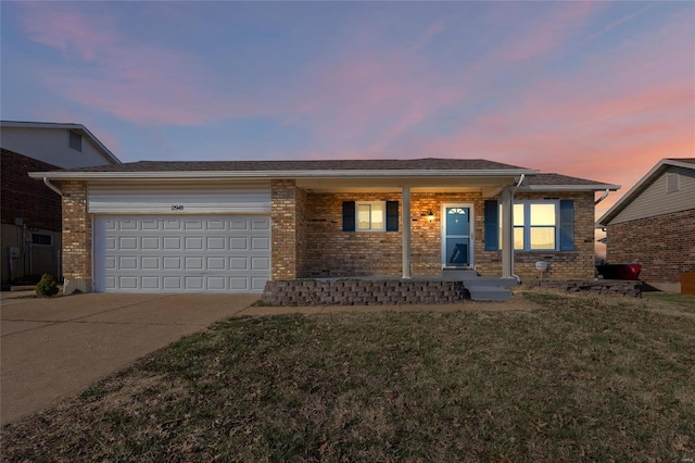 single story home featuring a yard, brick siding, concrete driveway, and an attached garage