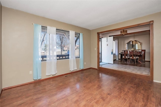 unfurnished room featuring visible vents, baseboards, and wood finished floors