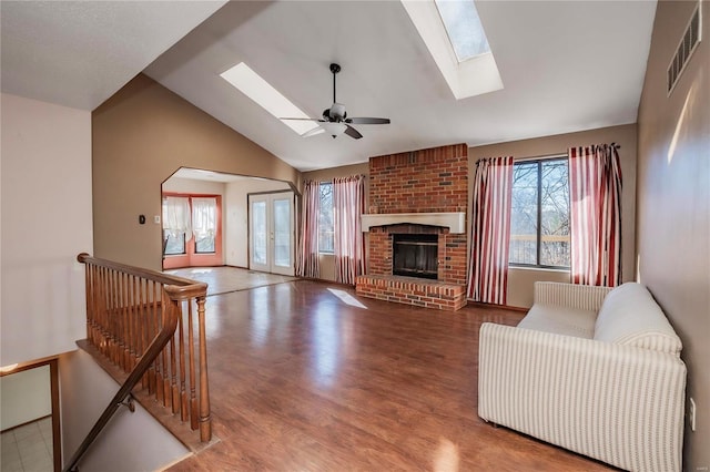 living area with a healthy amount of sunlight, a fireplace, visible vents, and wood finished floors