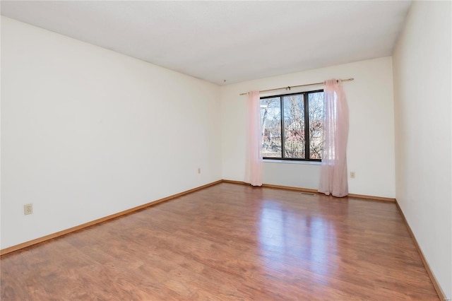 empty room with visible vents, baseboards, and wood finished floors