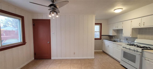 kitchen featuring light tile patterned floors, white cabinets, light countertops, white gas stove, and a sink