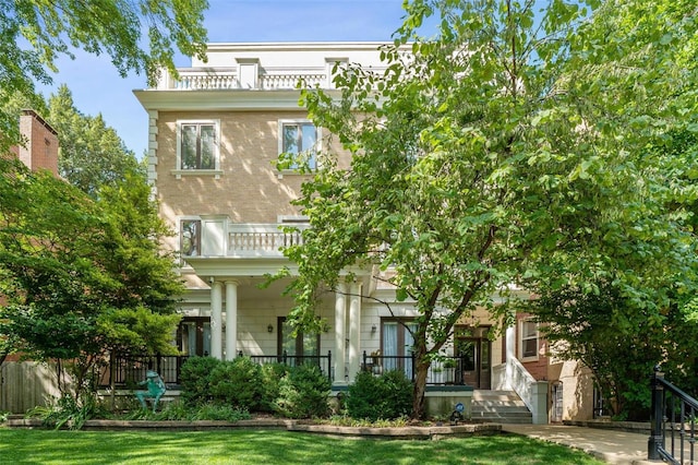 rear view of property with a lawn and a balcony