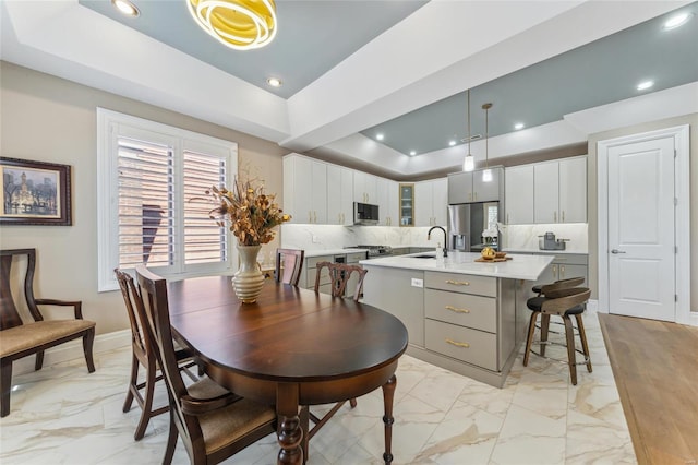 dining space featuring recessed lighting, marble finish floor, a raised ceiling, and baseboards