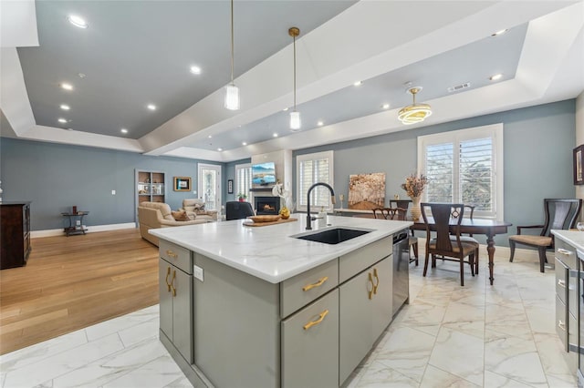 kitchen featuring a sink, visible vents, a raised ceiling, and gray cabinetry