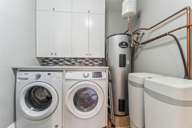 clothes washing area featuring cabinet space, water heater, and washer and clothes dryer