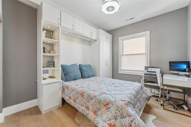 bedroom featuring light wood-style floors, visible vents, and baseboards