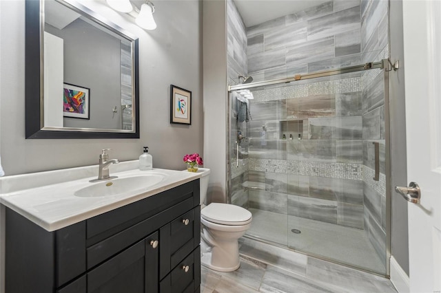 bathroom with a shower stall, vanity, and toilet