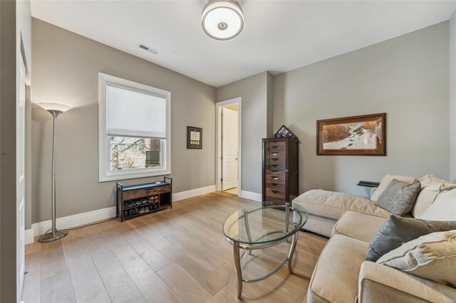 living room featuring wood finished floors, visible vents, and baseboards