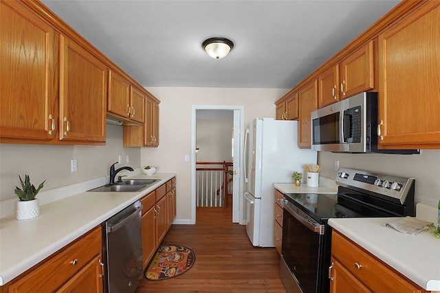 kitchen featuring stainless steel appliances, dark wood-style flooring, brown cabinets, and a sink