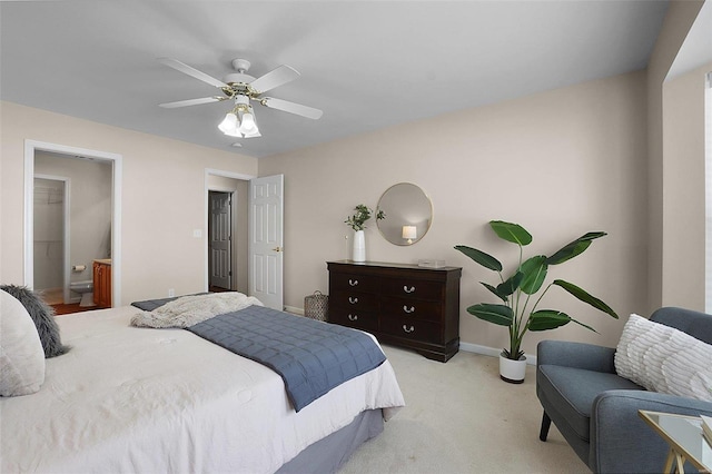 carpeted bedroom featuring a ceiling fan, ensuite bath, and baseboards