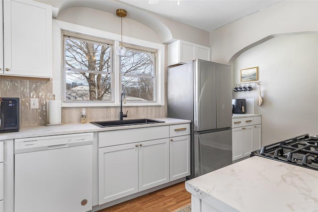 kitchen with a sink, white cabinets, freestanding refrigerator, dishwasher, and pendant lighting