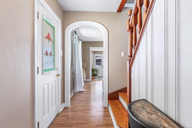 foyer featuring arched walkways, stairway, plenty of natural light, and wood finished floors