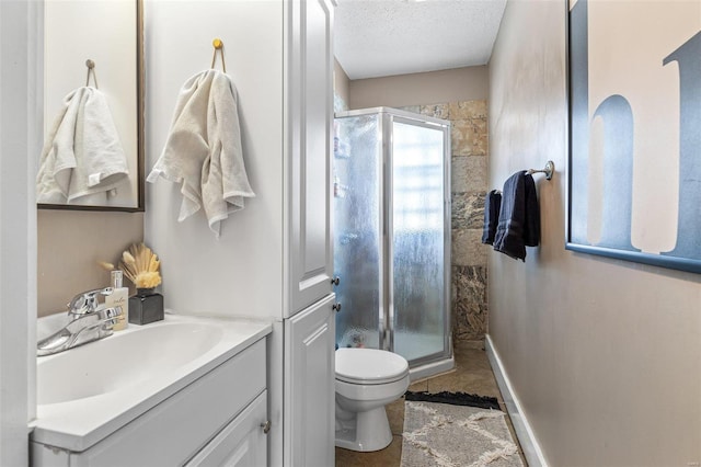 bathroom featuring a stall shower, baseboards, toilet, a textured ceiling, and vanity