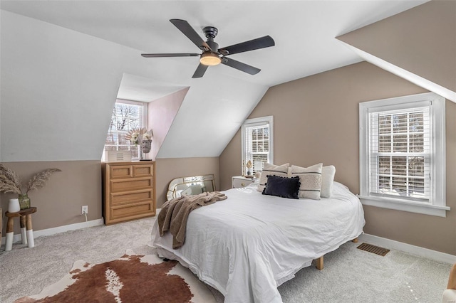 bedroom featuring light colored carpet, vaulted ceiling, baseboards, and multiple windows