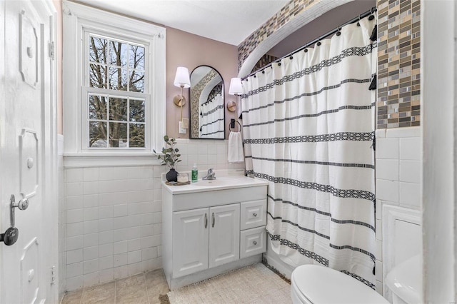 bathroom with tile walls, curtained shower, wainscoting, vanity, and tile patterned flooring