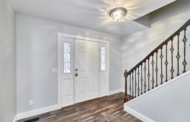 foyer entrance with dark wood-style flooring, visible vents, baseboards, and stairs