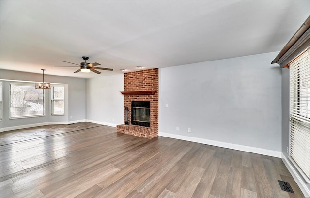 unfurnished living room featuring a fireplace, wood finished floors, visible vents, and baseboards