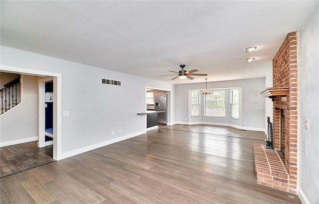 unfurnished living room with stairway, a fireplace, wood finished floors, and visible vents