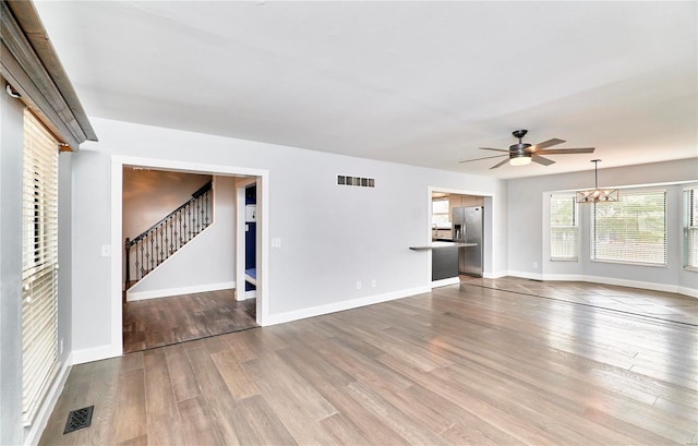 unfurnished living room featuring stairway, visible vents, and wood finished floors