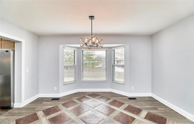 unfurnished dining area featuring an inviting chandelier, wood finished floors, and baseboards