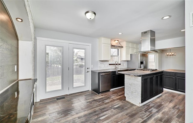 kitchen with island range hood, dark wood finished floors, decorative backsplash, a kitchen island, and appliances with stainless steel finishes