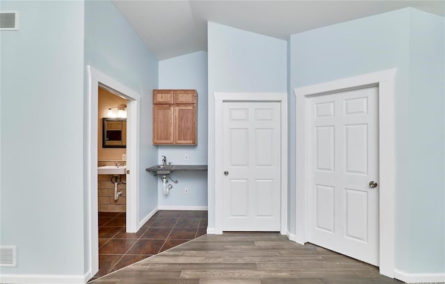 interior space with baseboards, visible vents, vaulted ceiling, and dark wood-style flooring