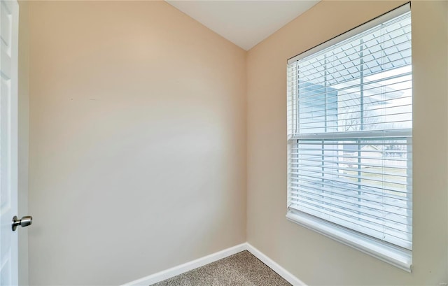 carpeted empty room featuring baseboards