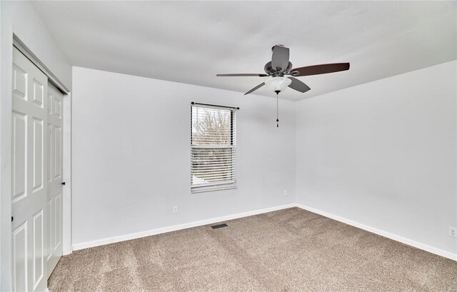 carpeted empty room with baseboards, visible vents, and ceiling fan