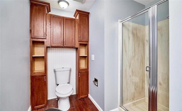 bathroom with toilet, a shower stall, baseboards, and wood finished floors