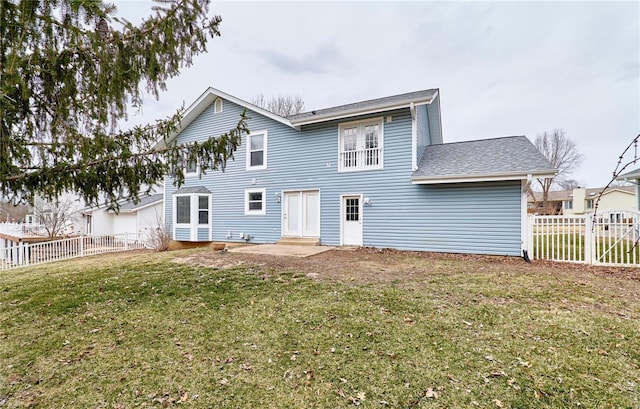 back of house with entry steps, a fenced backyard, and a lawn