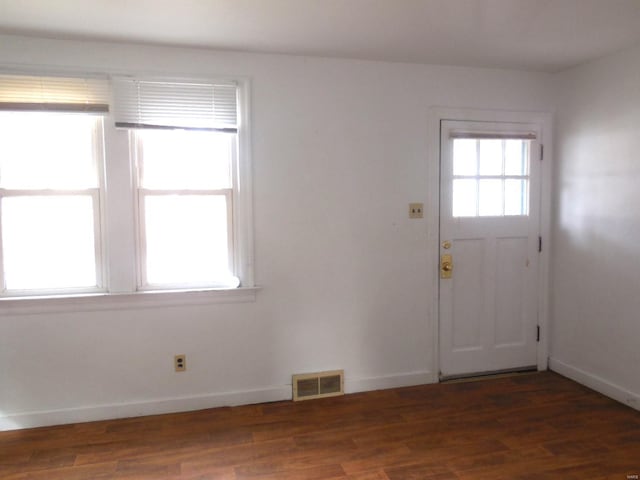 interior space with dark wood-type flooring, visible vents, and baseboards