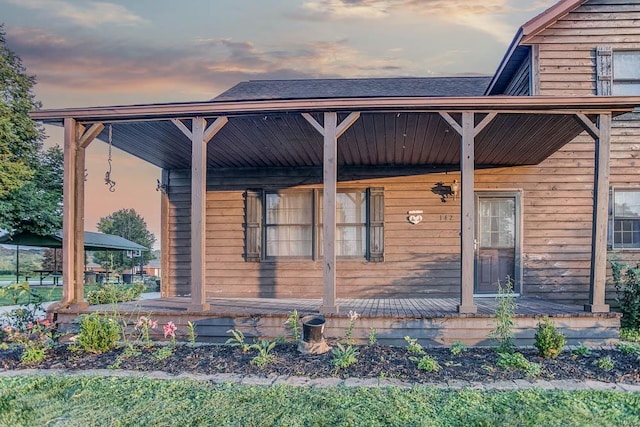 exterior space with a porch and roof with shingles