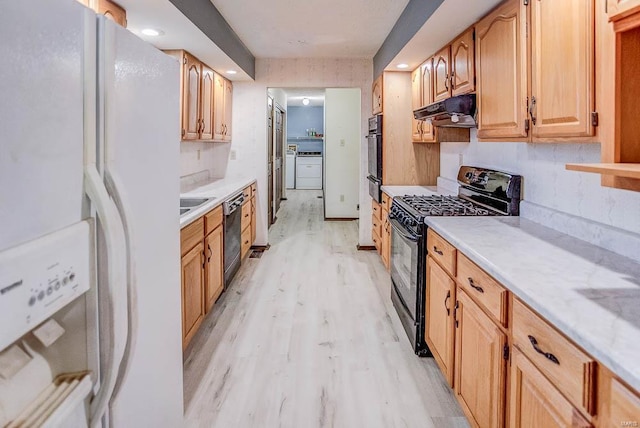 kitchen with black appliances, light wood finished floors, a sink, and under cabinet range hood