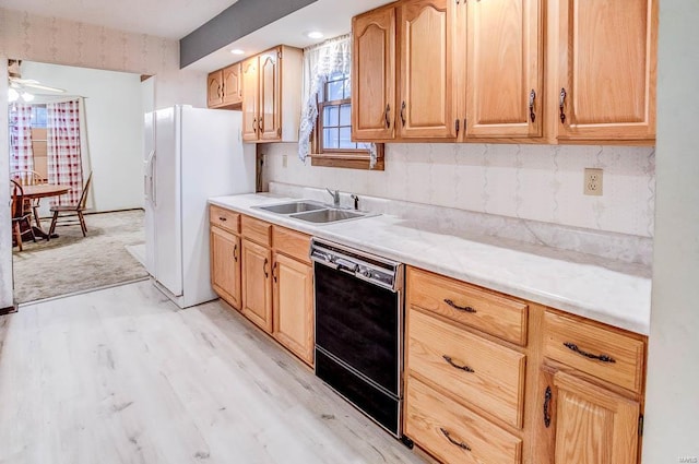 kitchen featuring light wood finished floors, light countertops, a sink, white fridge with ice dispenser, and dishwasher