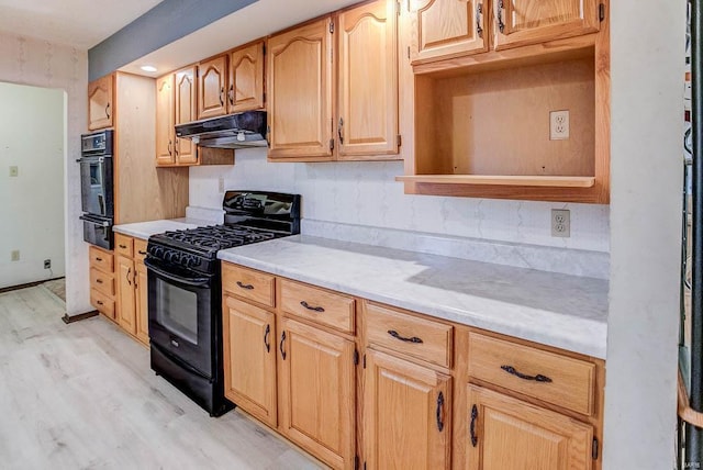 kitchen featuring a warming drawer, light wood finished floors, light countertops, under cabinet range hood, and black appliances