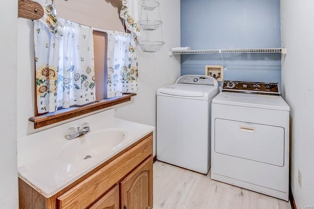 clothes washing area featuring washer and clothes dryer, light wood-type flooring, and a sink