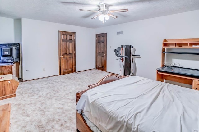 bedroom with light carpet, visible vents, a textured ceiling, and a ceiling fan