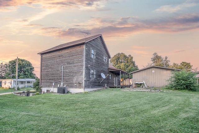 property exterior at dusk featuring a yard and central air condition unit