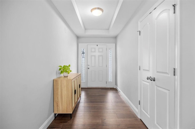 doorway to outside with a tray ceiling, baseboards, and dark wood finished floors