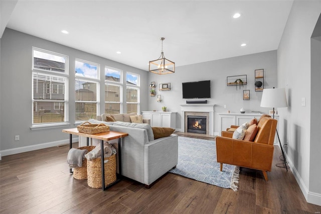 living area featuring dark wood finished floors, a glass covered fireplace, recessed lighting, and baseboards