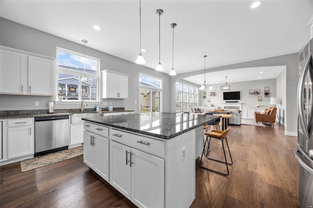 kitchen featuring dark wood-style floors, a kitchen island, appliances with stainless steel finishes, and open floor plan